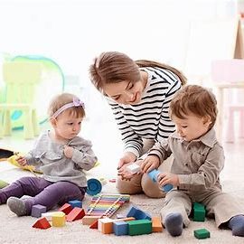 Une mère joue avec deux jeunes enfants et des jouets colorés sur un tapis.